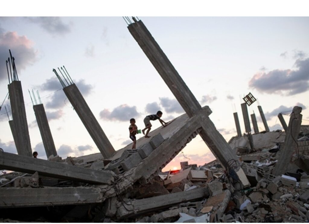 Two kids climbing and playing on building rubble in the Gaza strip at sunset during an Israel-Hamas War. 